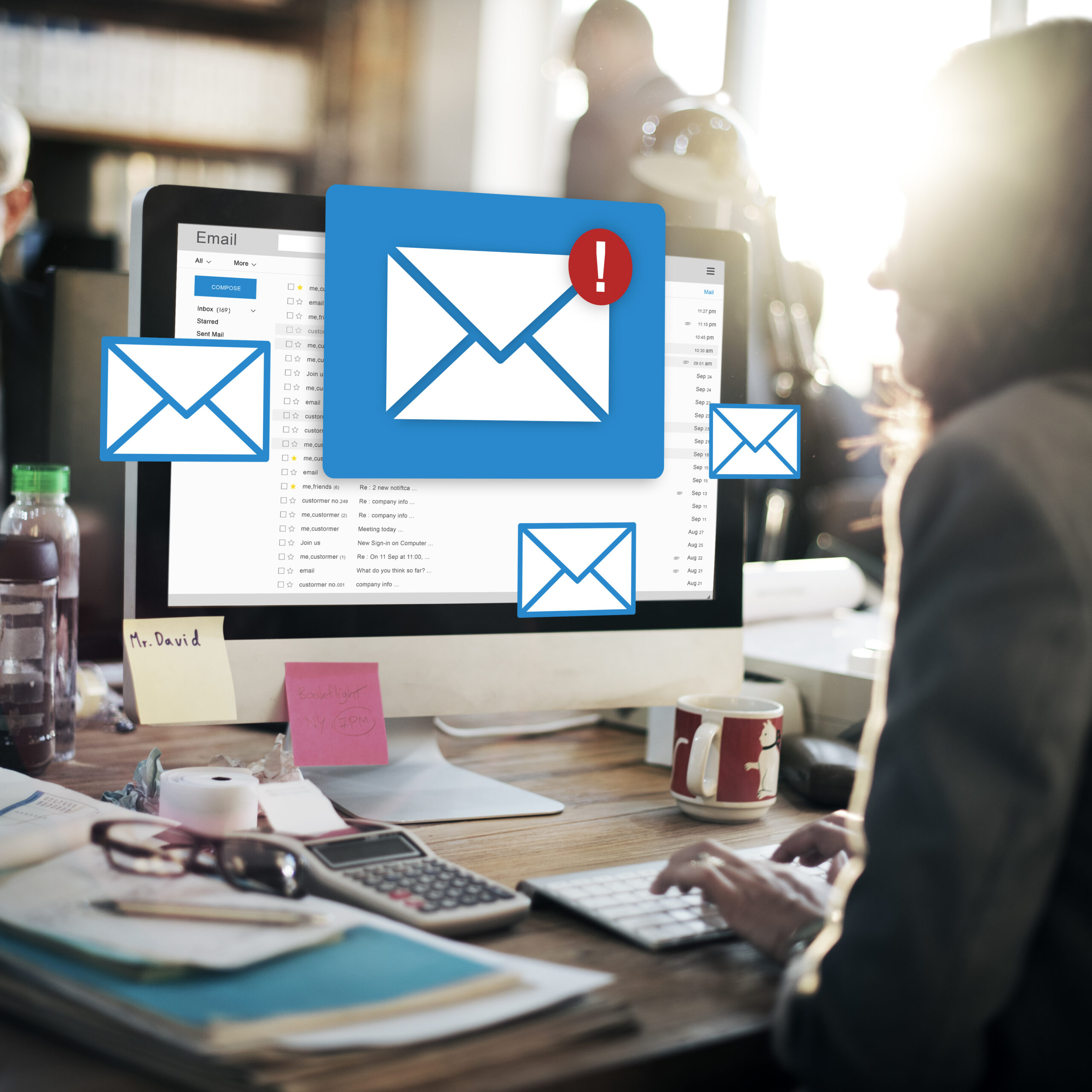 Business professional checking emails on desktop with multiple email icons, illustrating the concept of email list segmentation and inbox engagement.